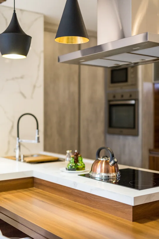 Cocina moderna con isla, mesada blanca y lámparas colgantes negras — proyecto Apto Sérgio e Lizandra, por Coletivo Arquitetura