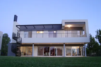Fachada moderna con escalera caracol y amplios ventanales — proyecto Casa Laguna - Barrio Laguna del Sol (Tigre, Buenos Aires) German Salas arquitect, por German Salas arquitectura