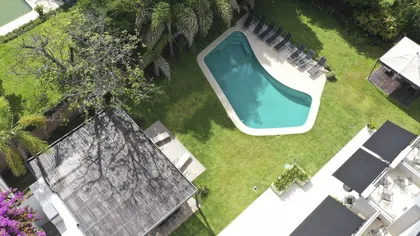 Área de piscina residencial moderna con vegetación exuberante — proyecto Villa Isidro Hotel Boutique & Spa, por Hermann Arquitectos, en San Isidro