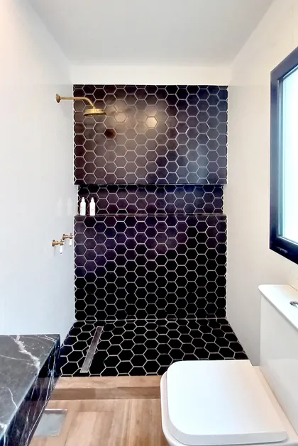 Baño moderno industrial con azulejos hexagonales negros y grifería de latón — proyecto Casa CN451, por EZ architects, en Belén de Escobar