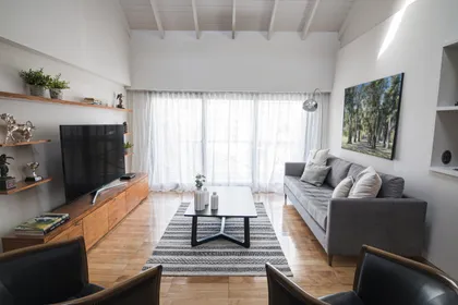 Living moderno con gran ventanal y mueble de madera — proyecto Navarro, por ST Arquitectas, en CABA