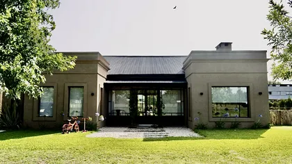 Casa moderna de una planta con grandes ventanales y jardín verde — proyecto Los Jazmines Pilar del Este, por Marconi Silva Arquitectos, en Pilar del Este