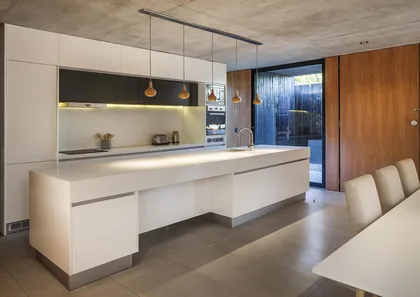 Cocina moderna con isla blanca y techo de hormigón expuesto — proyecto Casa MF, por V2 Arquitectos, en City Bell
