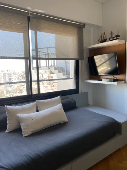 Dormitorio moderno con cama baja, cortinas de rollo y TV — proyecto Juncal, por MDBK Arquitectura, en Recoleta