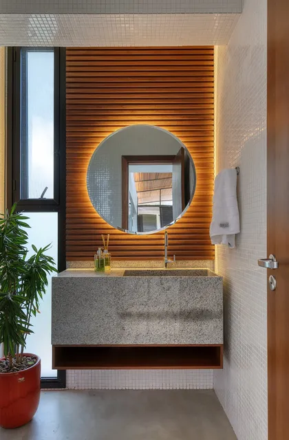 Baño moderno con espejo circular iluminado y mesada de mármol gris — proyecto Casa das Pedras, por Tetro Arquitetura