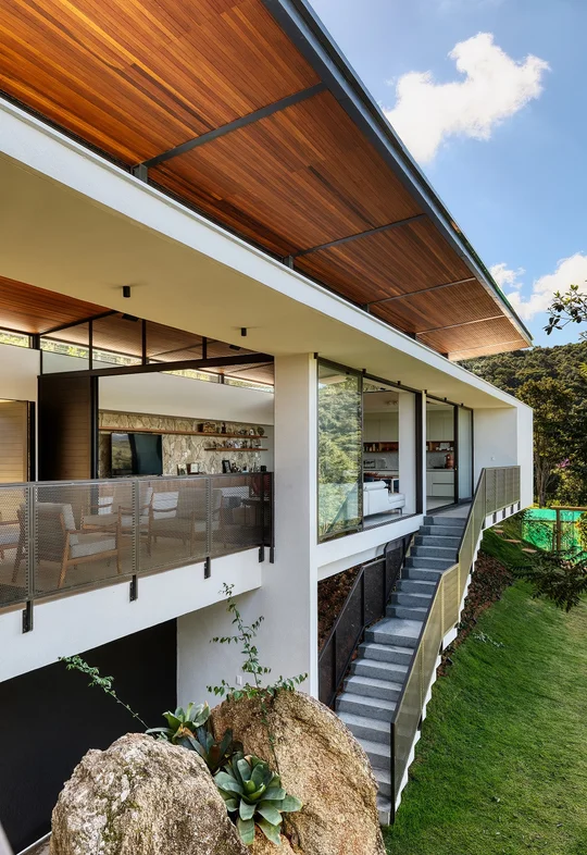 Fachada contemporánea con terraza, techo madera y grandes ventanales — proyecto Casa das Pedras, por Tetro Arquitetura