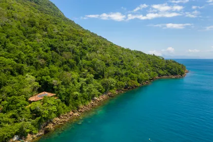 Acantilado verde frondoso junto a mar turquesa cristalino — proyecto Casa da Ilha, por Miguel Capanema Arquitetura