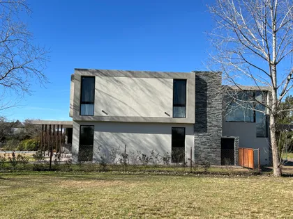 Casa moderna de dos pisos con fachada mixta de hormigón y piedra — proyecto CASA LR 138 - SOFITEL LOS CARDALES, por Carolina Depetris, en B2814 Los Cardales