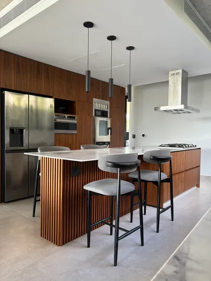 Cocina moderna con isla de listones de madera y mármol — proyecto Carpinchos - Estudio Gambotto, por ABEJA CONCEPT, en Nordelta