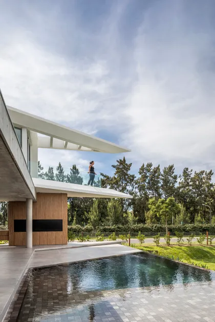 Terraza moderna con balcón en voladizo y piscina junto a vegetación — proyecto Casa Didney, por Jorgelina Tortorici & asoc., en Nordelta