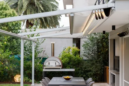 Patio moderno con horno de pizza y pérgola retráctil — proyecto TOLDER - PERGOLAS, por Argentina en Obra 2024, en Rincón de Milberg
