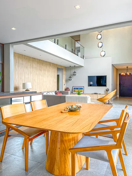 comedor moderno de doble altura con mesa ovalada de madera — proyecto Casa com pele de vidro, por Edilma Costa, en Piracaia