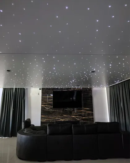 Sala moderna con techo de estrellas y sofá curvo negro — proyecto Cine hogareño , por Clausen deco , en B1648 Tigre