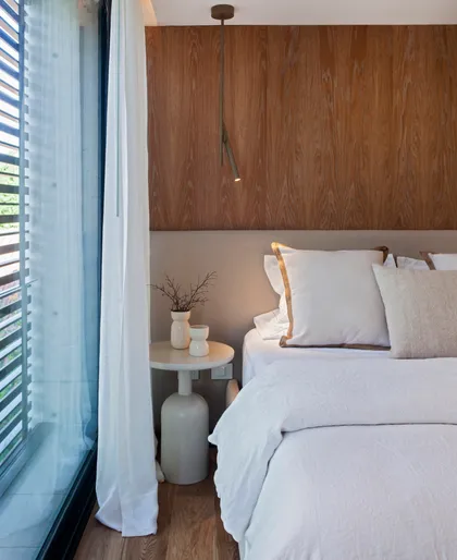 Dormitorio moderno con pared de madera y cama blanca — proyecto CASA AH, por GMARQ, en Garin