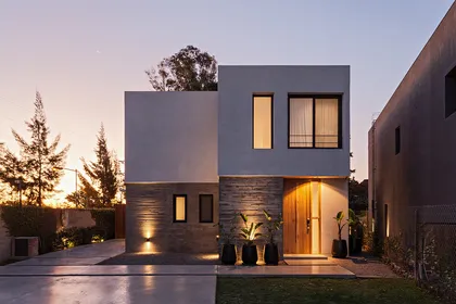 Fachada moderna de casa de dos plantas con volúmenes geométricos y luces cálidas — proyecto CASA RDV, por Rastro Estudio, en San Isidro