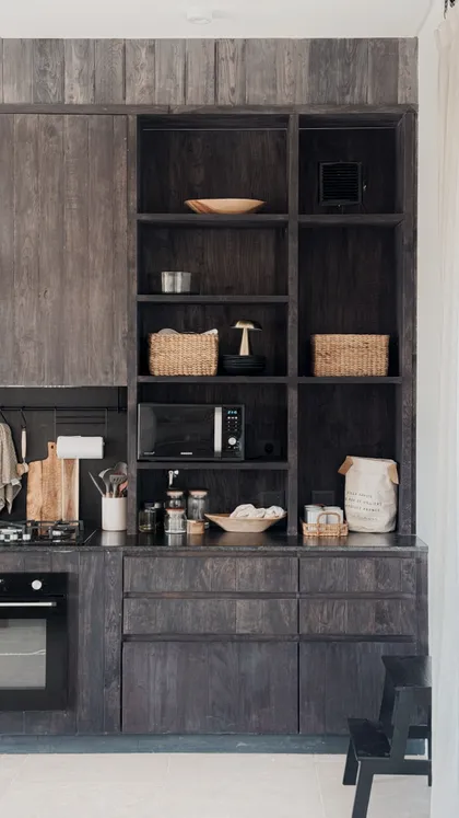 Cocina rústica moderna con muebles de madera oscura y estanterías abiertas — proyecto El Refugio, por Grupo Pauta Arquitectura, en Pinamar