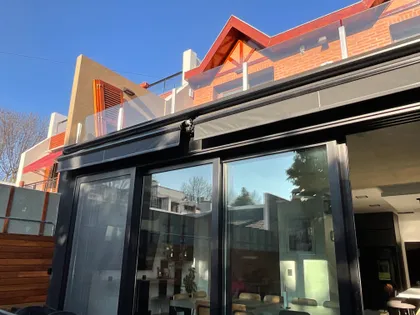 Fachada moderna con toldo retráctil y ventanas de piso a techo — proyecto JUAN AGUSTIN GARCIA, por Novoa Clerici arquitectos, en Buenos Aires