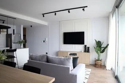 Living moderno con sofá gris y mesa de comedor de madera — proyecto Departamento Airbnb, por Jeitinho Estudió Creativo, en La Plata