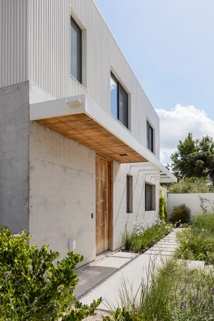 Fachada moderna de hormigón y metal con vegetación exuberante — proyecto CASA CC, por Rastro Estudio, en San Isidro