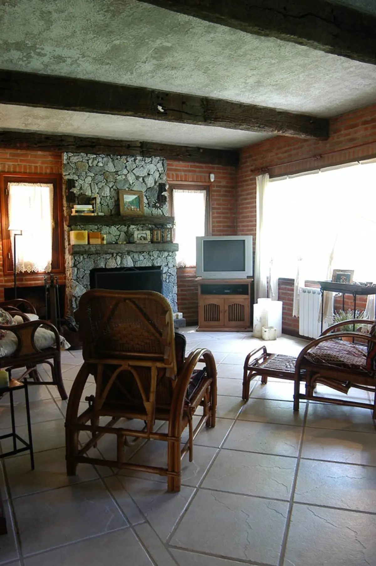 Sala rústica com vigas de madeira e lareira de pedra — projeto Casa Cariló 2004, por Hugo Zawadski Arquitectos, em Cariló