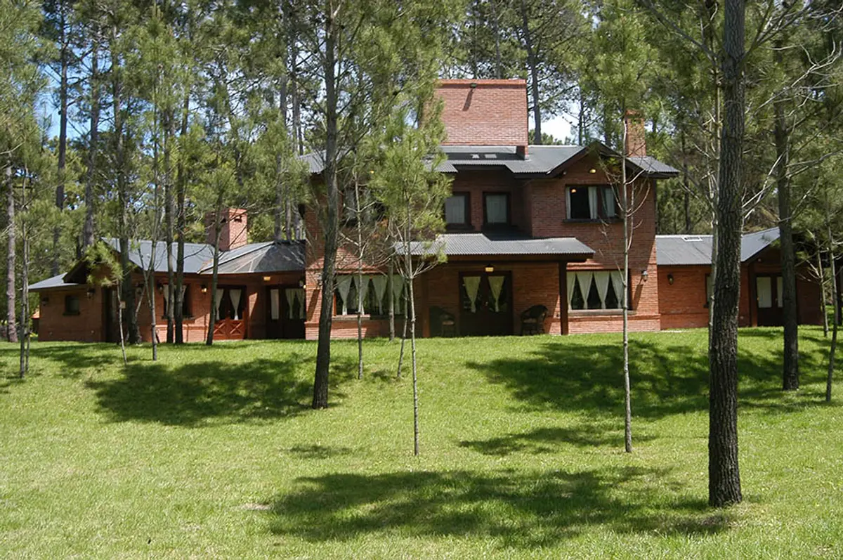 Casa rústica no campo cercada por floresta com detalhes em madeira — projeto Casa Cariló 2004, por Hugo Zawadski Arquitectos, em Cariló