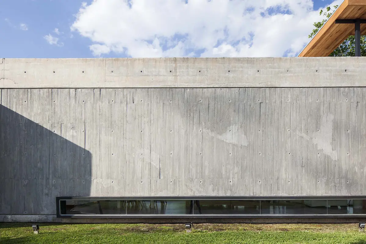 Fachada de concreto aparente com janela longa e telhado de madeira — projeto Santa Isabel, por Arfuso Arquitectos, em Ingeniero Maschwitz