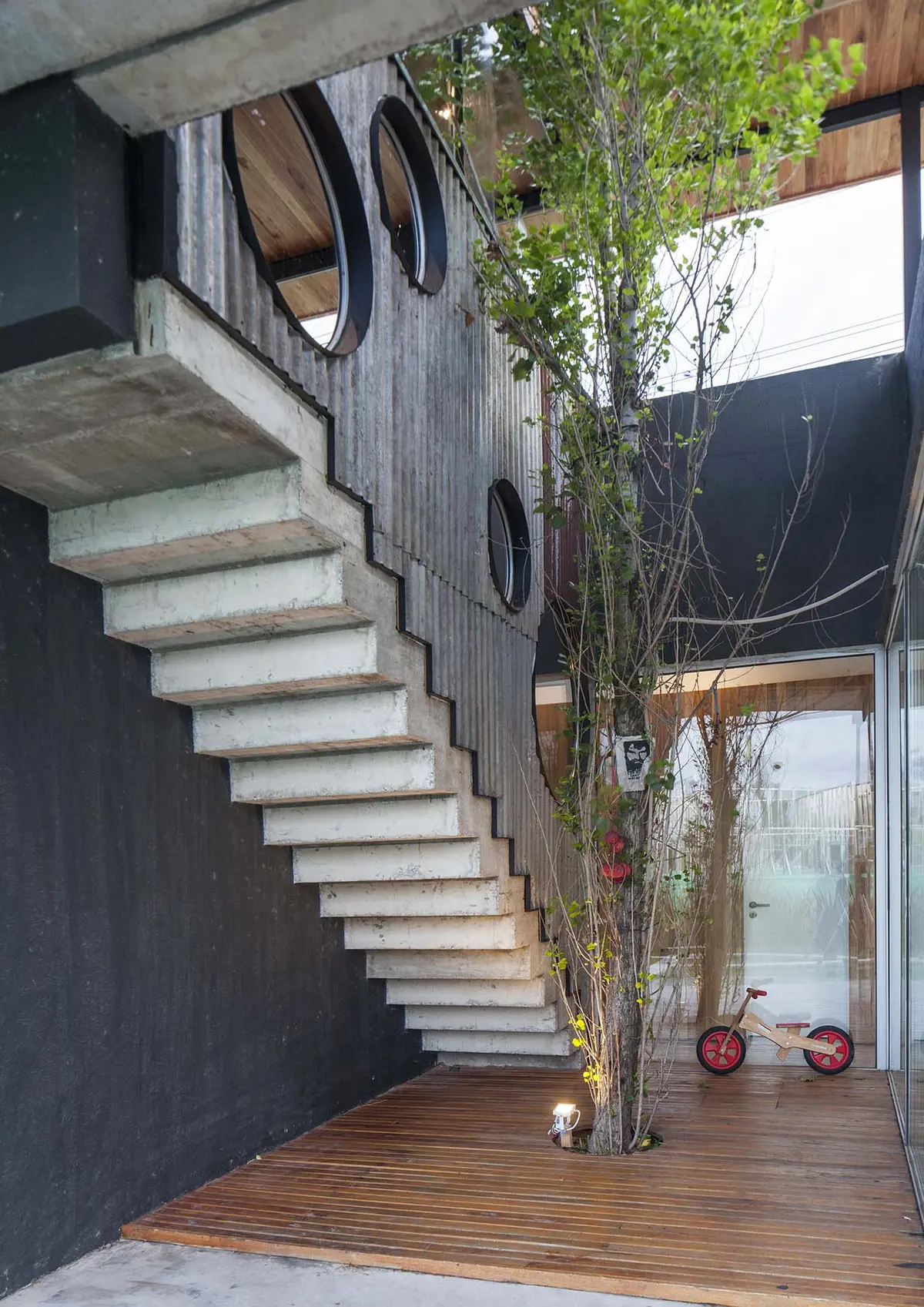 Escada de concreto em balanço com janelas circulares e árvore — projeto Santa Isabel, por Arfuso Arquitectos, em Ingeniero Maschwitz