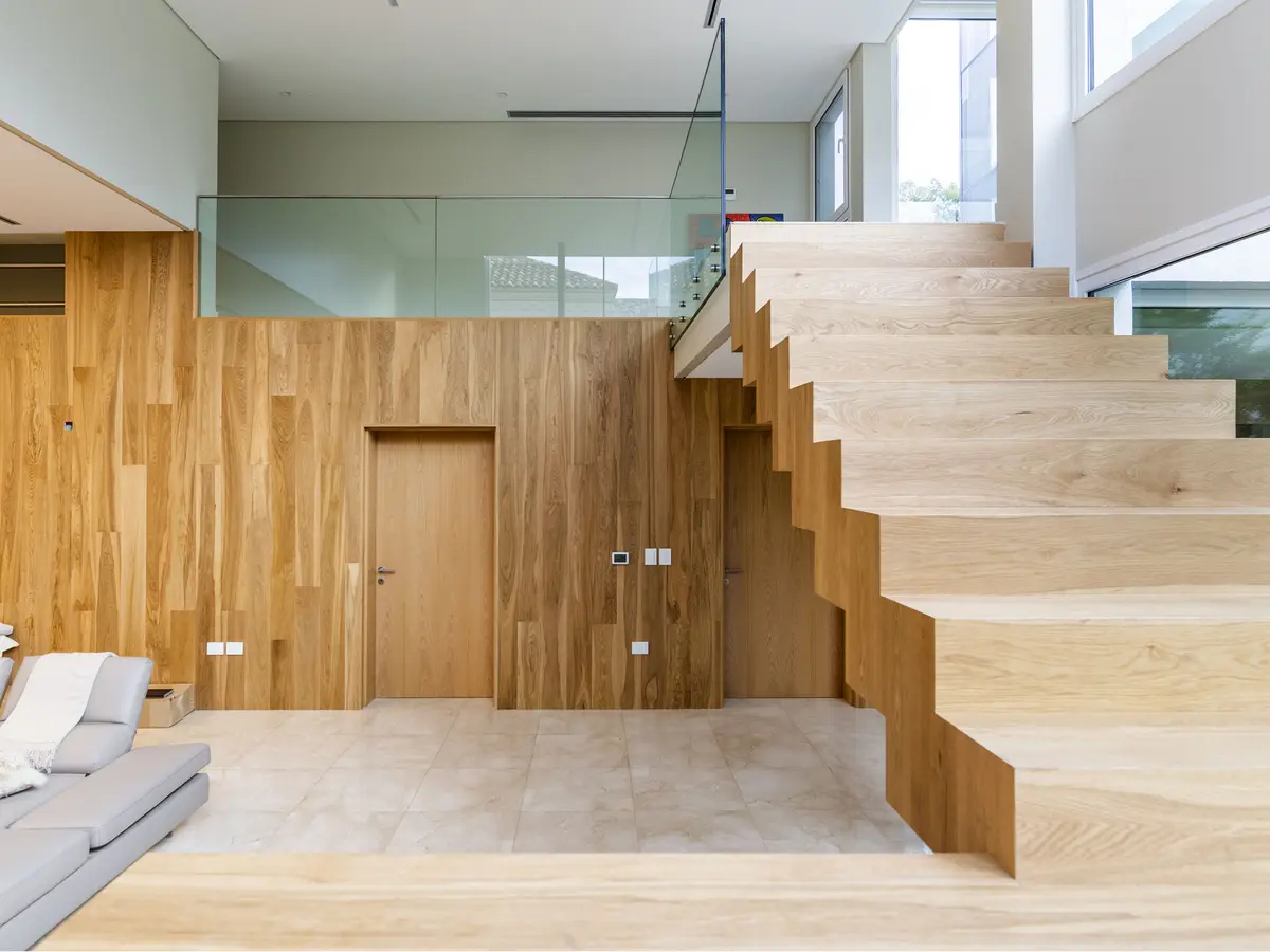 Escada flutuante moderna em madeira em interior de pé-direito duplo — projeto Las Caletas, por Arfuso Arquitectos, em Nordelta