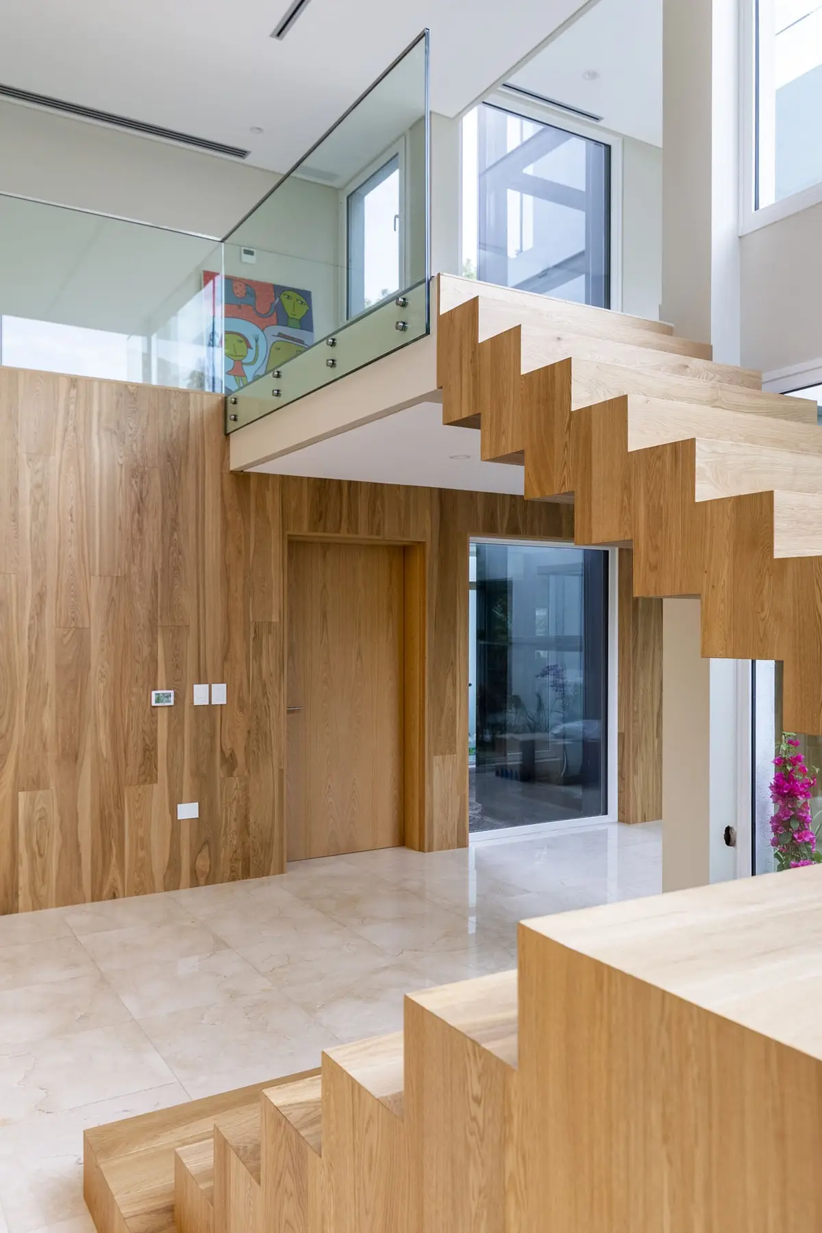 Escalera flotante moderna con paredes de madera y barandillas de vidrio — proyecto Las Caletas, por Arfuso Arquitectos, en Nordelta