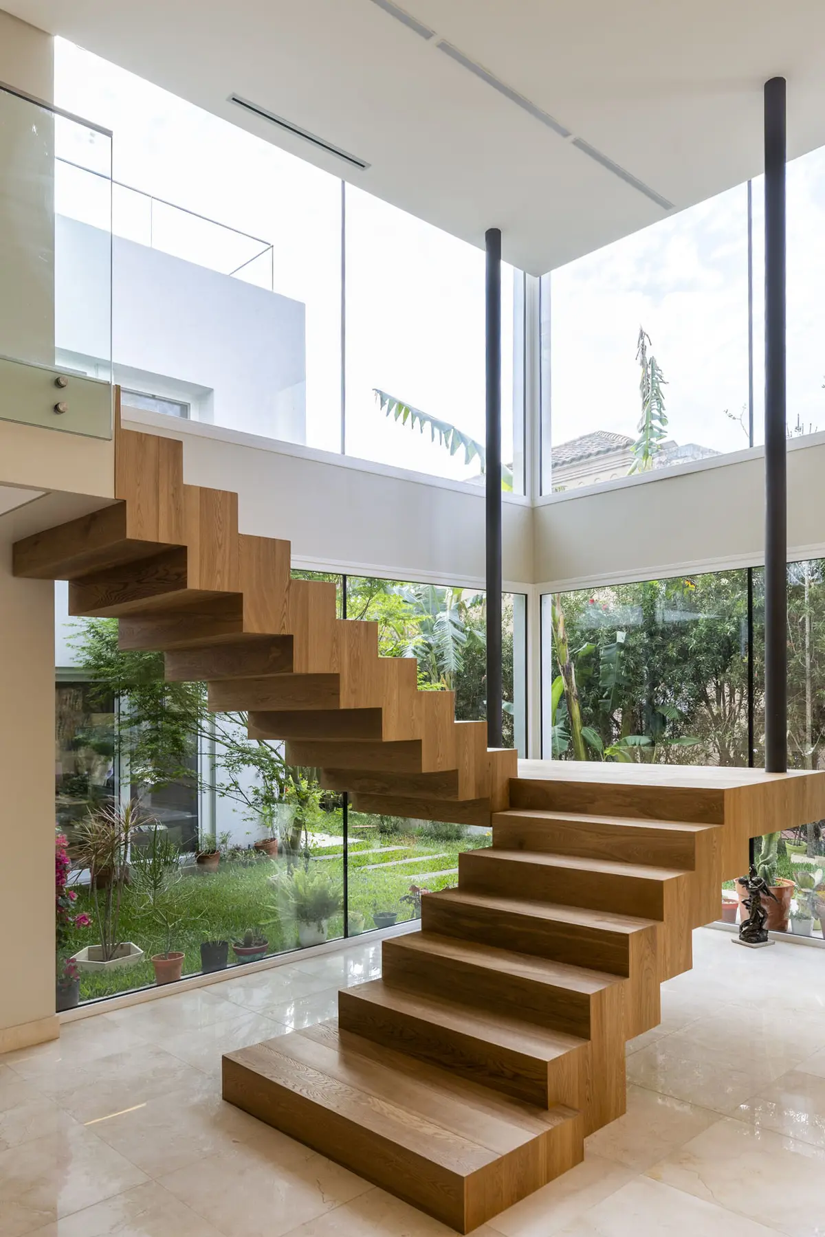 escalera flotante de madera en casa moderna con ventanales — proyecto Las Caletas, por Arfuso Arquitectos, en Nordelta