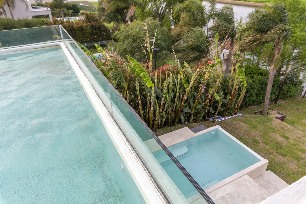 piscina infinita moderna com vegetação exuberante e deck de madeira — projeto Las Caletas, por Arfuso Arquitectos, em Nordelta