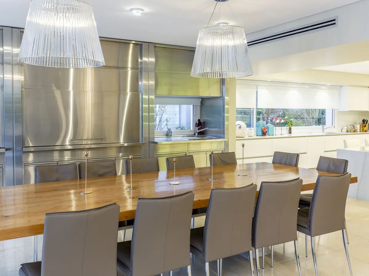 Comedor moderno con cocina industrial y luces colgantes — proyecto Las Caletas, por Arfuso Arquitectos, en Nordelta