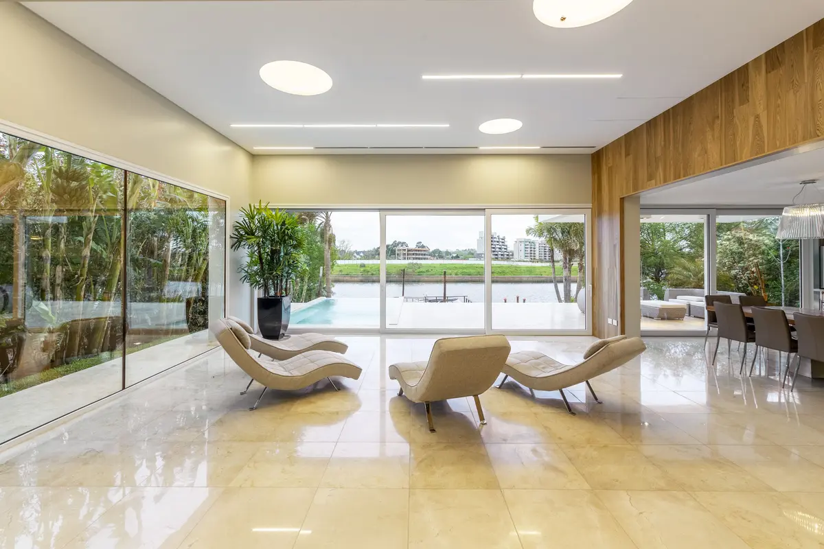 Sala de estar moderna com vista para jardim tropical e poltronas curvas — projeto Las Caletas, por Arfuso Arquitectos, em Nordelta