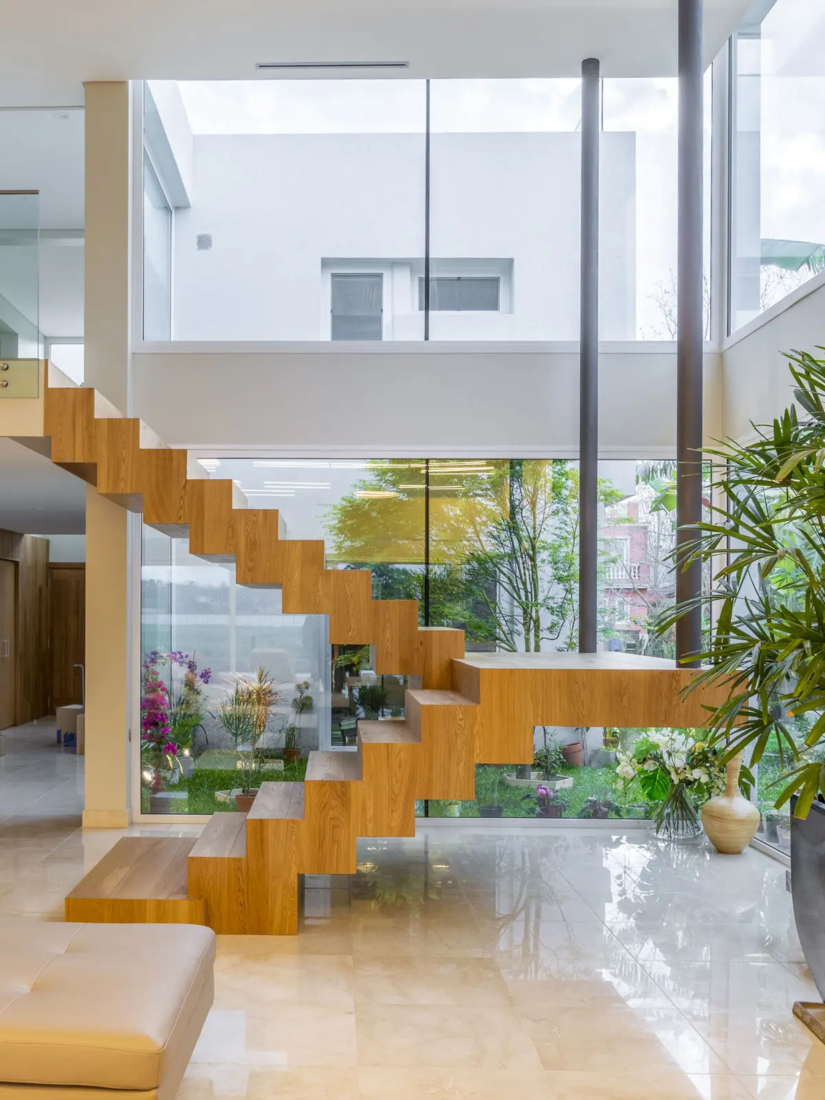Escada flutuante de madeira em casa moderna com jardim interno e janelas do chão ao teto — projeto Las Caletas, por Arfuso Arquitectos, em Nordelta