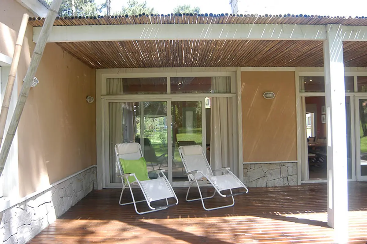Varanda de madeira com espreguiçadeiras — projeto Casa Cariló 2005, por Hugo Zawadski Arquitectos, em Cariló