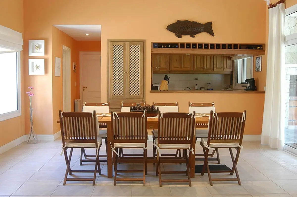 Sala de jantar mediterrânea com móveis de madeira e paredes cor de terracota — projeto Casa Cariló 2005, por Hugo Zawadski Arquitectos, em Cariló