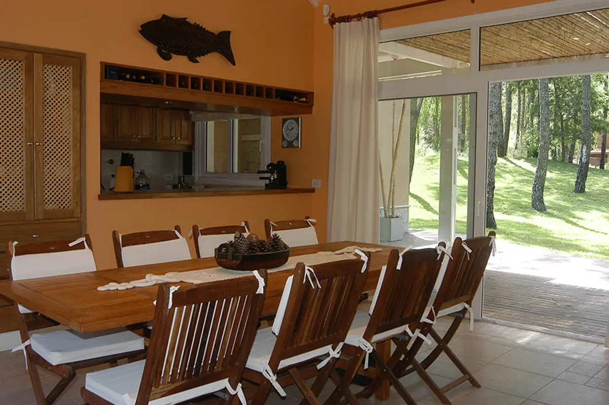 Comedor rústico moderno con mesa de madera y sillas — proyecto Casa Cariló 2005, por Hugo Zawadski Arquitectos, en Cariló