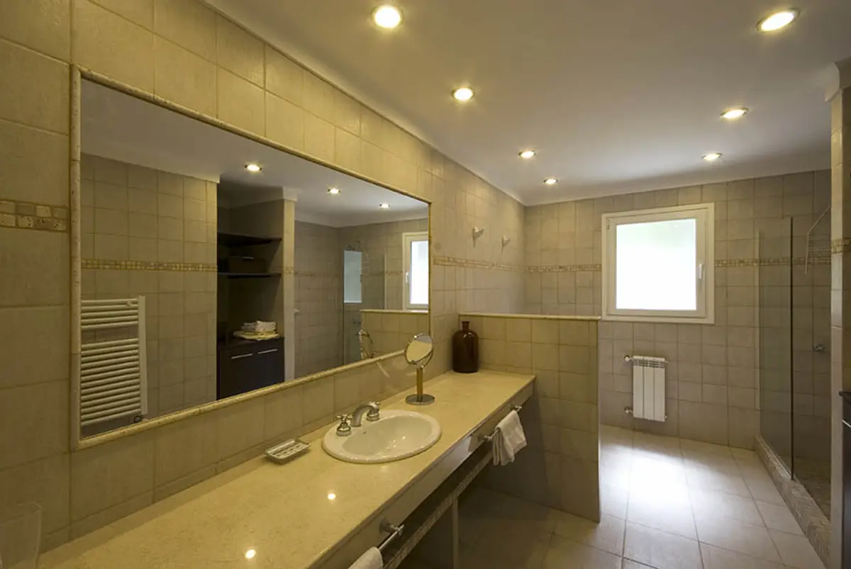Banheiro moderno com espelho grande, pia de cerâmica e detalhes em pedra — projeto Casa Cariló 2007, por Hugo Zawadski Arquitectos, em Cariló
