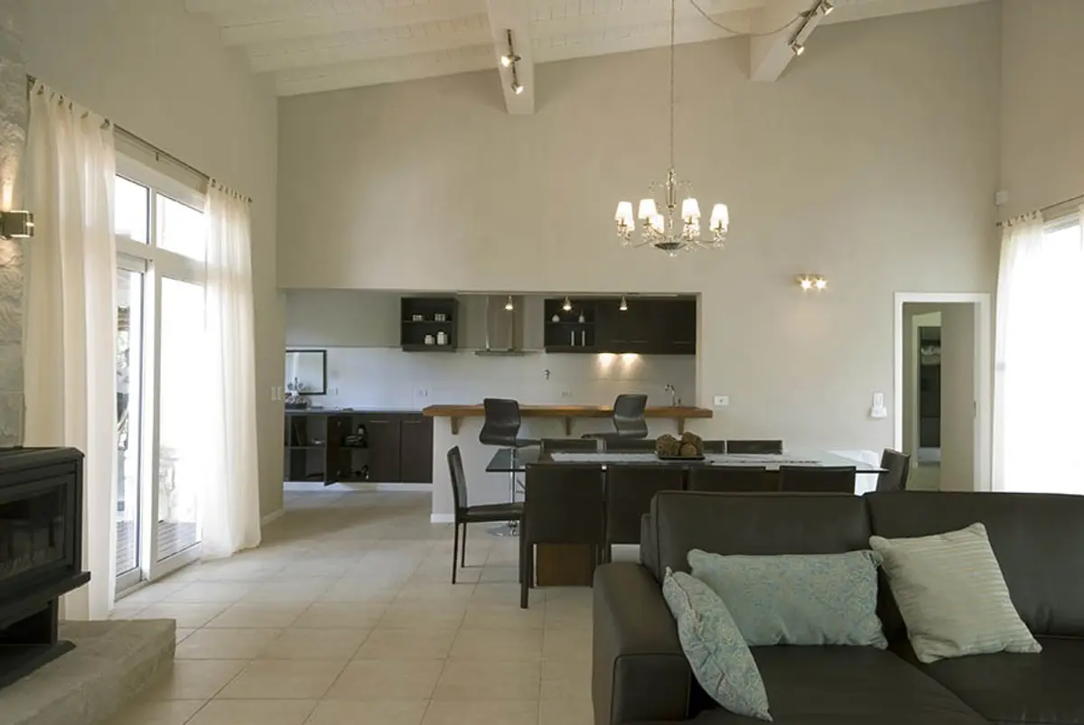 Living comedor integrado con chimenea y vigas expuestas — proyecto Casa Cariló 2007, por Hugo Zawadski Arquitectos, en Cariló