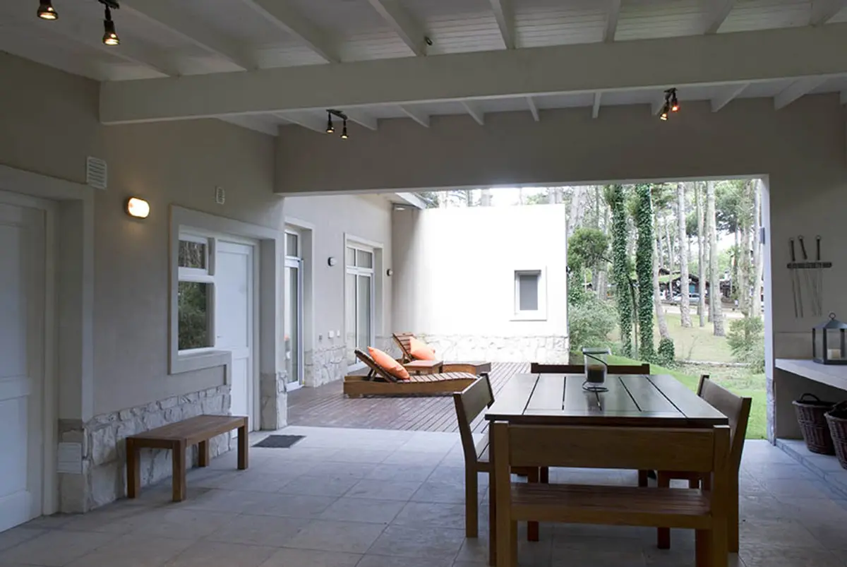 Pérgola moderna com sala de jantar externa e vista para floresta — projeto Casa Cariló 2007, por Hugo Zawadski Arquitectos, em Cariló