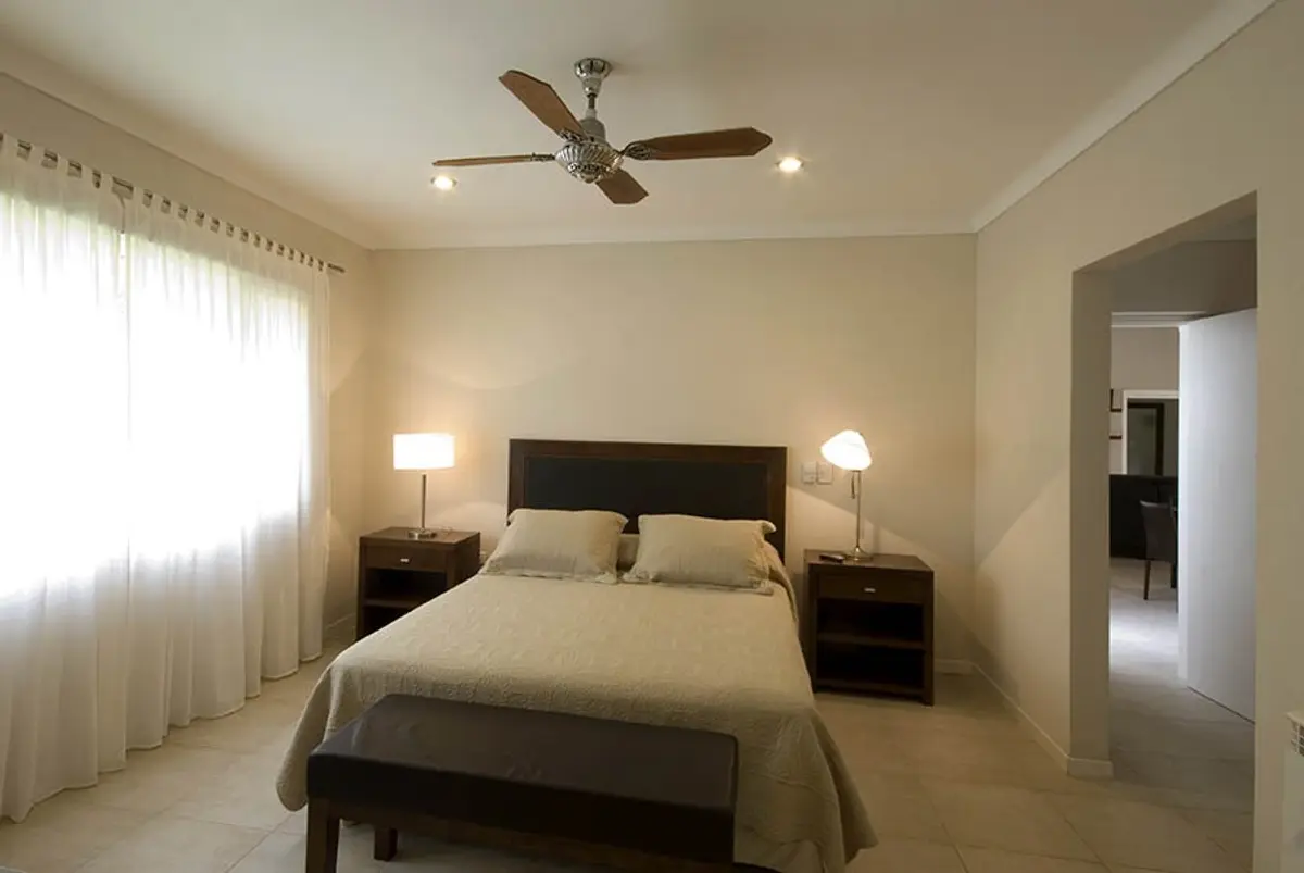 quarto de hotel moderno, tons neutros, ventilador de teto — projeto Casa Cariló 2007, por Hugo Zawadski Arquitectos, em Cariló