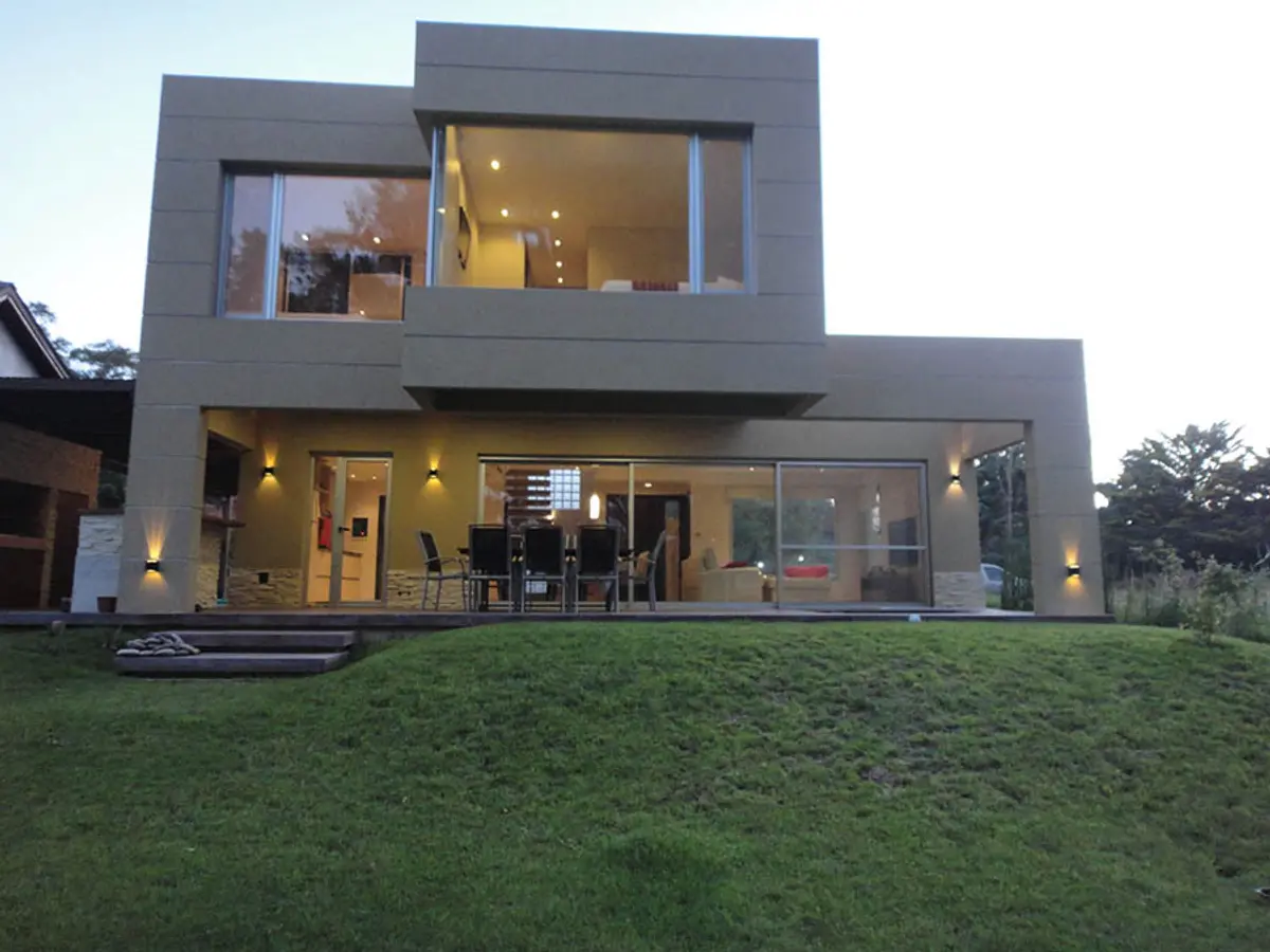 fachada moderna com grandes janelas e gramado — projeto Casa Valeria del Mar 2015, por Hugo Zawadski Arquitectos, em Valeria del Mar