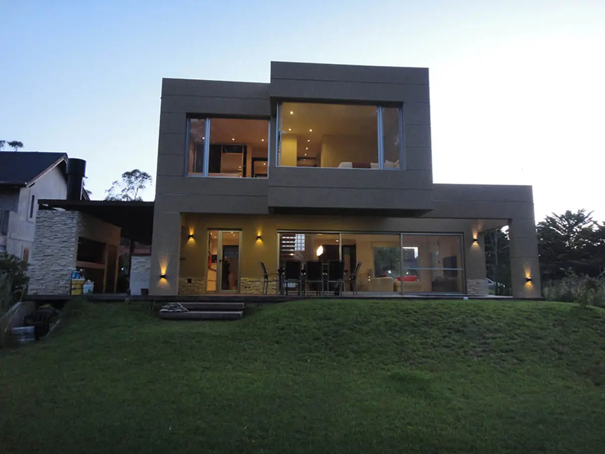 Casa moderna de dois andares com volumes geométricos e janelas amplas — projeto Casa Valeria del Mar 2015, por Hugo Zawadski Arquitectos, em Valeria del Mar