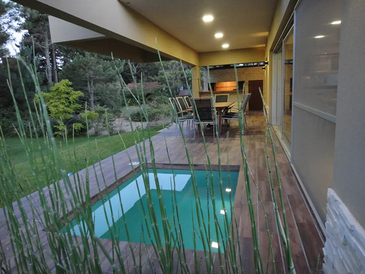 Quincho moderno con piscina y deck de madera, rodeado de césped alto — proyecto Casa Valeria del Mar 2015, por Hugo Zawadski Arquitectos, en Valeria del Mar