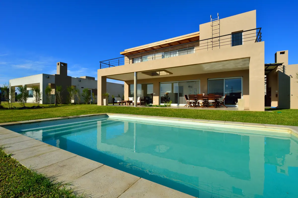 Fachada moderna com piscina e céu azul — projeto Los Alisos 41, por Carlos Fiamberti, em Los Alisos