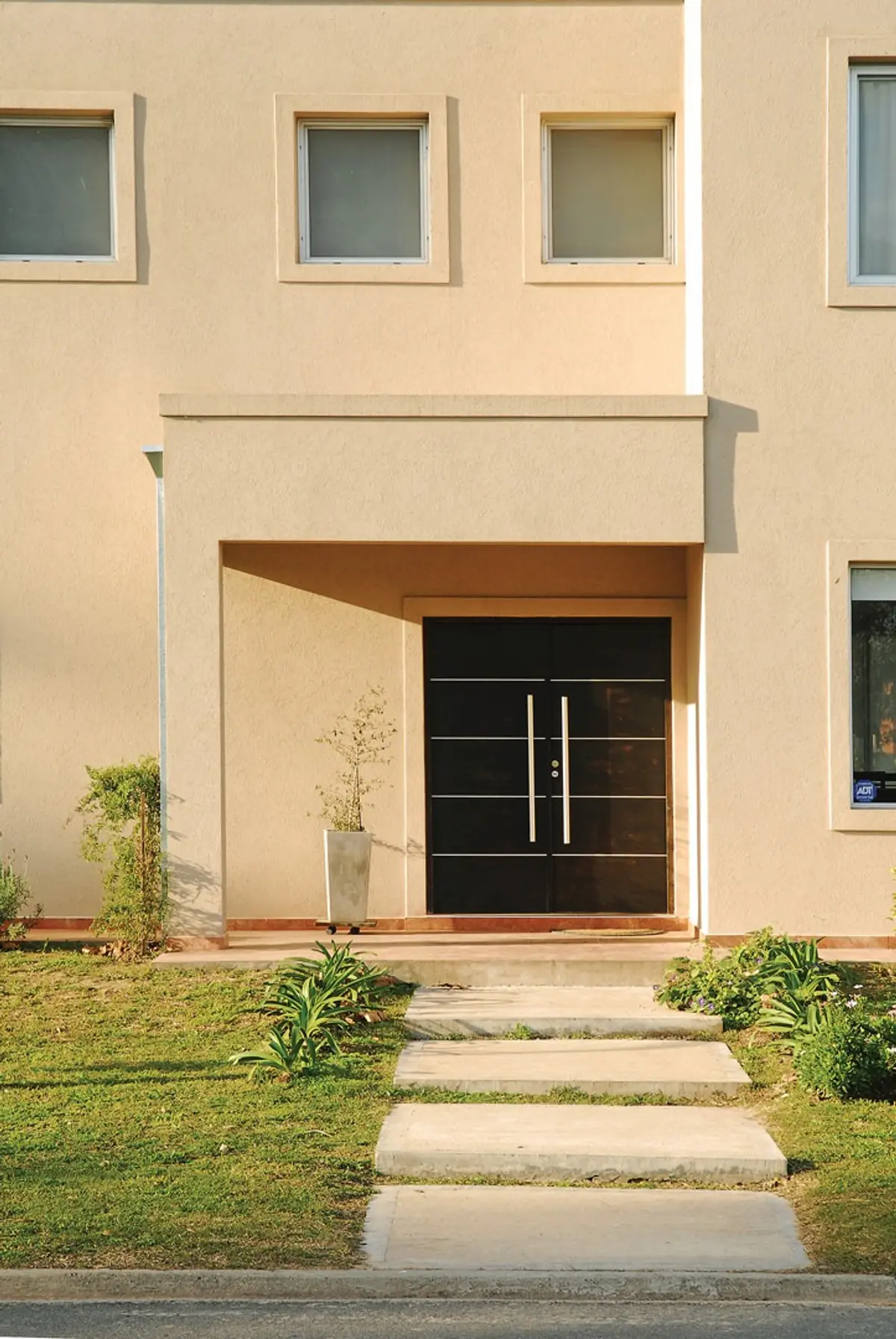 Fachada moderna com porta dupla e detalhes geométricos — projeto Casa El Recodo, por Fhee Construcciones, em Garin