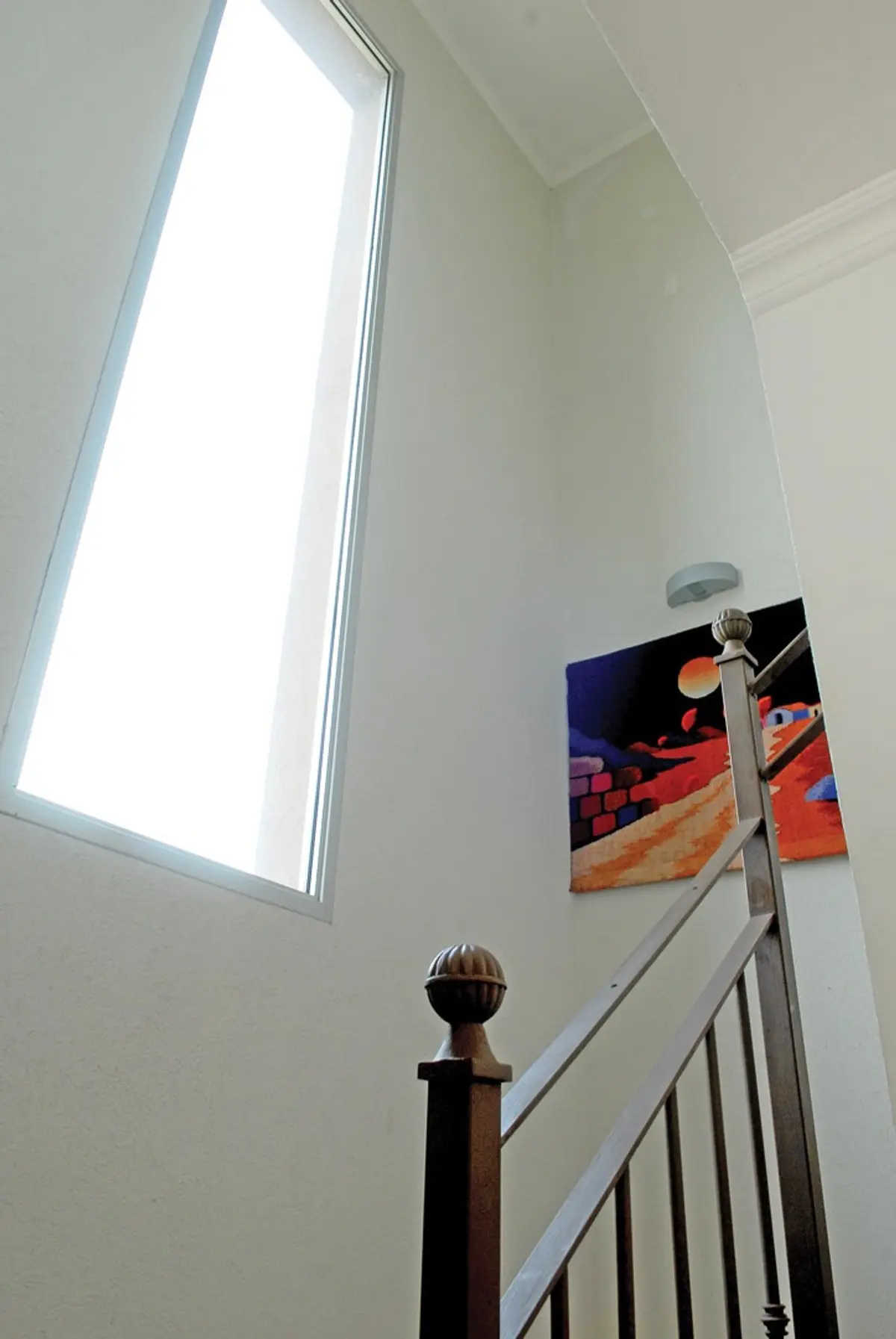 Corredor com escada, janela alta, quadro abstrato e corrimão de madeira — projeto Casa El Recodo, por Fhee Construcciones, em Garin