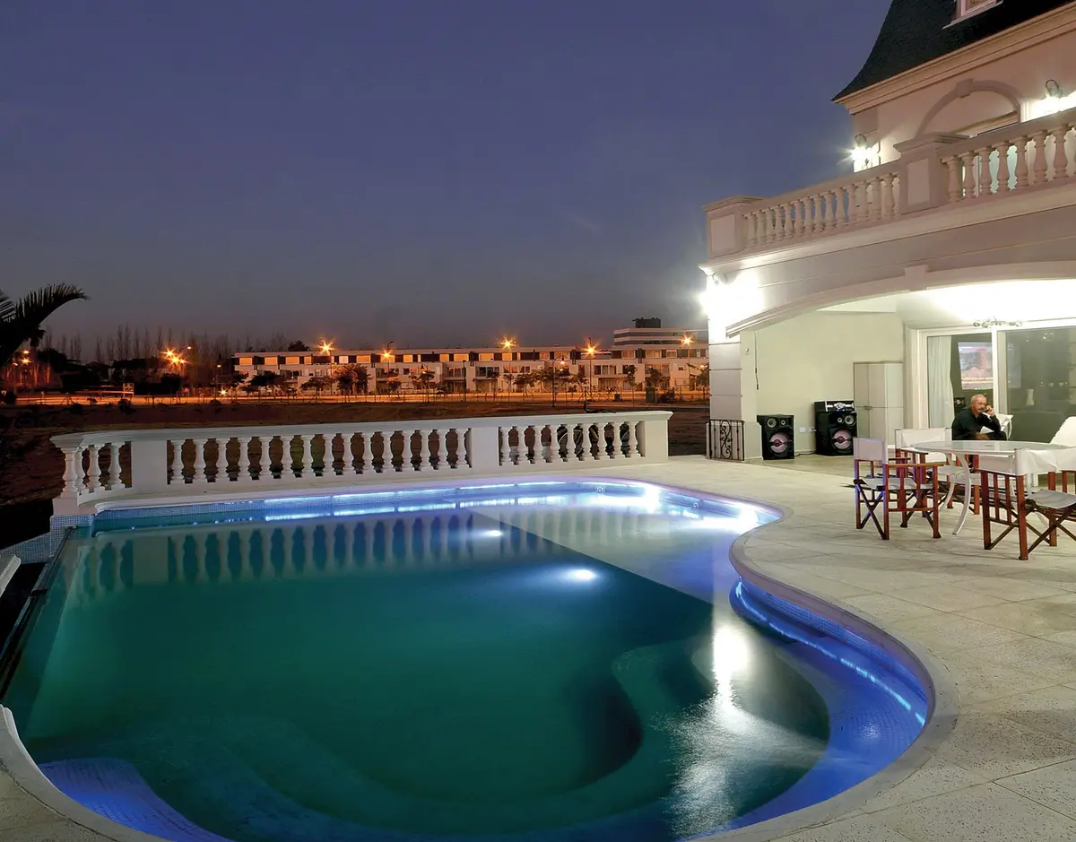 Piscina iluminada en área exterior moderna con fachada blanca — proyecto Casa 4, por Fhee Construcciones, en Nordelta