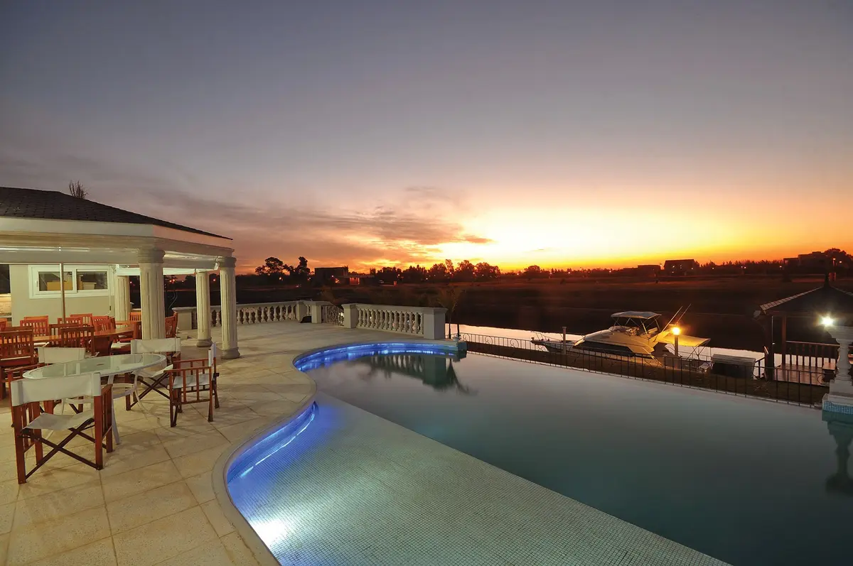 Terraza de piscina con cena al atardecer junto al mar — proyecto Casa 4, por Fhee Construcciones, en Nordelta