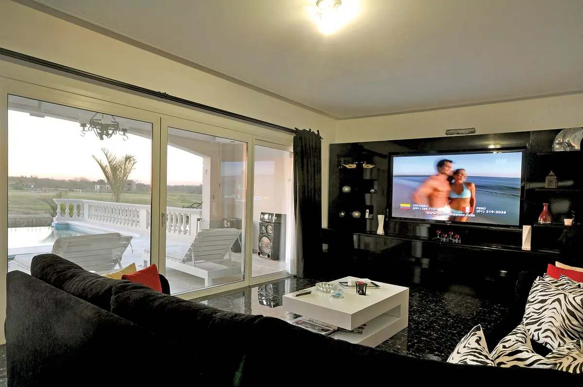 Sala de estar moderna con vista al mar y grandes ventanales — proyecto Casa 4, por Fhee Construcciones, en Nordelta